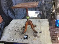 Full view of antique wooden side table with adjustable top and tripod base on outdoor surface.