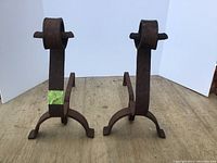 Pair of antique cast iron end irons with upright supports and horizontal bar