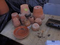 Multiple clay pots of different sizes arranged on a table with some soil residue visible.