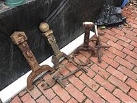 Set of five decorative iron parts arranged on ground, showing varied finial tops and rusted condition.