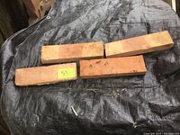Four terra cotta tiles laid out on a dark tarp, showing size and condition, with a yellow label '51' on one tile.