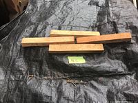 Rectangular terra cotta tiles laid on a black tarp with three tiles aligned horizontally for size reference.