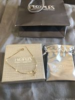 10k gold bracelet with heart and arrow pendant, Peoples branded packaging including box, pouch, and shopping bag.