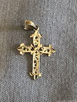 Front view of gold cross pendant showing ornate filigree design and 10K stamp on bale.