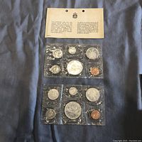 Two sealed coin sets with six coins each, displaying obverse and reverse sides, along with instructional certificate for each set.