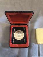 Front view of the 1973 RCMP silver dollar in its original red velvet case with transparent holder showing the RCMP design and dates 1873-1973