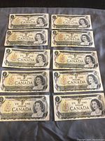 Ten Canadian one dollar bills arranged in two groups to show front with Queen Elizabeth II portrait and denomination in English and French.