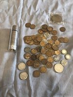 Overall view of the lot showing tube of rolled coins, loose American wheat cents, Buffalo nickel, V nickel, and Canadian coins.
