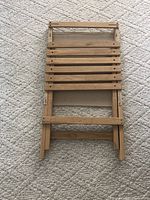 Wooden chair folded flat showing slatted wood seat and folding mechanism