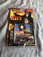 Front of blister packaging showing Gene Simmons and KISS branding with die-cast car visible inside.
