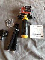Full lot overview showing the camera mounted on the floating hand grip, mini tripod, microSD card in case, two camera mount adapters and instruction manual.