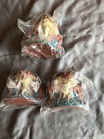 Three Jar Jar Binks squirt heads in original sealed clear plastic bags, placed on a fabric background.