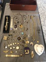 Wide view showing the entire jewelry lot spread on cloth, including watches, clips, boxes, and assorted pieces.