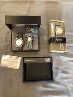 Overview of lot showing two watches in box with warranty papers, black wallet in Champs box, and another watch in Denver Hayes box.
