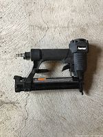 Side view of first Powerwise pneumatic nail gun showing grip, trigger, and nail magazine.