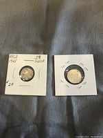 Photo showing two coins: 5 cent silver coin from 1945 and a 10 cent coin dated 1942, both in coin holders.
