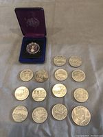 Overall view of all coins and presentation case laid out on fabric.