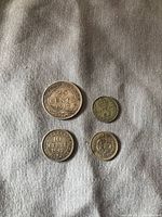 Top view of four coins: Newfoundland 25 cents 1917, Newfoundland 10 cents 1945, British 5 pence, and British 3 pence