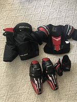 Bauer junior hockey gear set including shoulder pads, hockey pants, elbow pads, and shin guards all in size M.
