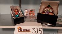 Two Christopher Radko Starlight Family collectible glass ornaments displayed in original boxes: a Cinderella carriage and an angel figure, including tags and packaging insert.