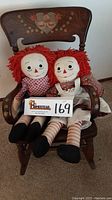 View of Raggedy Ann and Andy dolls seated on the rocking chair highlighting the dolls and handpainted design.