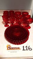 Photo of the full lot showing six small wine glasses, six champagne glasses and four ruby red plates, all with embossed patterns.