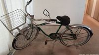 Full side view of the green vintage Sumner bicycle showing frame, rear basket, saddle, side mirror, fenders and pedals.