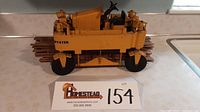 Side view of yellow pressed steel toy straddle truck carrying wooden lumber pieces, showing Hyster branding.