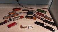 Overview of all vintage model train cars and locomotives arranged on table, showing a variety of colors and railroad markings including Santa Fe and Union Pacific.