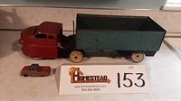 Side view of the large Wyandotte dump truck and the smaller Ford Tootsietoy placed next to a lot placard.