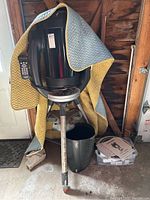 Telescope on tripod with yellow/gray protective cover draped, bin and manuals visible