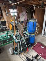 Wide side view of green plastic garden tool caddy holding various garden tools such as shovels, loppers, rakes, and weeders in a garage.