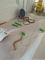 Overview: 10K gold bracelet, Sterling silver necklace, bangles and display frame on white cloth