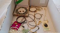 Overview shot showing all jewelry items in a box, cloisonné bracelet and earrings in a box, multiple watches, rings, necklaces, and other small jewelry pieces seen