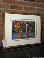 Framed painting shown full view against brick background