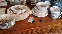 Multiple stack view of plates, cups, saucers in Royal Doulton Hampshire pattern on wooden table