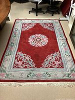 Full view of the vintage oriental wool rug with red central medallion and light gray floral border, showing pile thickness and fringe detail.