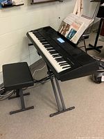 Full setup showing Casio WK-6500 keyboard on black X-style stand, padded bench next to it, and sheet music on the music rest.