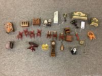 Top-down view of entire assortment showing various dollhouse furniture items arranged on a carpeted floor, including red chairs, sofas, lamps, and cabinets.