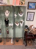 Full view of the IKEA glass display cabinet containing no items, showing three shelves, glass door with a small latch glued to it, minor surface wear on top, and metal frame.