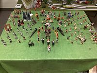 Overall view of the green cloth table covered with the full assortment of miniature figurines and scenery