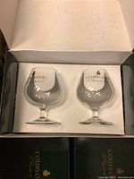 Open box showing two clear Courvoisier brandy glasses inside white molded packaging.