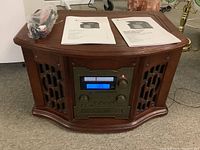 Full view of wooden record player radio console with instructions and cables on top.