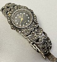 Close-up shot of the watch face and detailed silver band with marcasite stones, showing the missing stone defect.