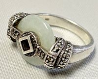 Close-up front angle of ring showing round jade and garnet stones with marcasite accent detail on silver band.