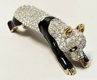 Front angled view of the crystal panda brooch showing its crawling pose, crystal body, black enamel legs, and gold-tone accents.