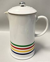 Front view of white stoneware French press with colored stripes and lid in place
