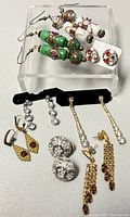 Various pairs of D'ORLAN vintage costume earrings arranged on a stand and surface, showing details and styles.