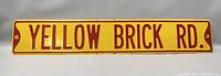 Full view of the vintage metal wall sign reading 'YELLOW BRICK RD.'