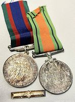 Two WW2 medals side-by-side with ribbons and clasp bar on white background.